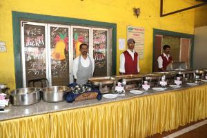 three men standing behind a buffet table with food at Horseland Hotel & Mountain Spa in Matheran +29 photos