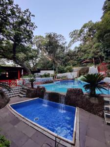 a swimming pool with a waterfall in a resort at Horseland Hotel & Mountain Spa in Matheran