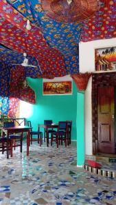 a room with tables and chairs and a colorful ceiling at Sweet Home in Kiwengwa