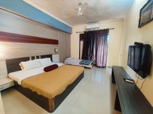a bedroom with a large bed and a television at Horseland Hotel & Mountain Spa in Matheran