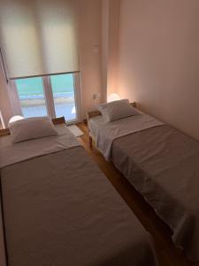 two beds in a room with two windows at Το Σπίτι στον Πεζόδρομο in Grevena