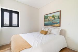 a bedroom with a white bed with a painting on the wall at Casa Pitoresca - Refugio Esposende in Braga