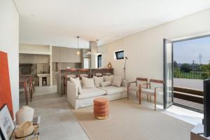 a living room with a white couch and a kitchen at Casa Pitoresca - Refugio Esposende in Braga