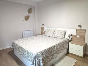 a white bedroom with a bed and a night stand at Martita Home in Zaragoza