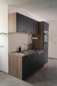 a kitchen with black and brown cabinets and a sink at Ferienwohnung Eifelmomente in Rittersdorf +22 photos