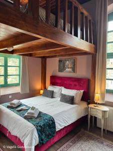 une chambre avec un grand lit à tête de lit rouge dans l'établissement The Old School Boutique Hotel, à Syrrako