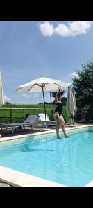 a woman sitting in a swimming pool with an umbrella at Arco Dei Nobili in Monforte dʼAlba +17 photos