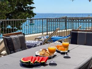 a table with a plate of food and two glasses of orange juice at Beachfront Villa San't Antonio Podaca in Podaca