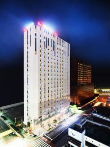 un edificio blanco alto con un cartel de hotel en la parte superior en Ibis Ambassador Busan Haeundae, en Busan