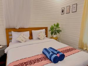 a bedroom with a bed with two blue towels on it at Bronze Bungalows in Gili Meno