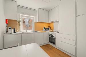 a white kitchen with white cabinets and a window at Trafaria Bliss in Trafaria