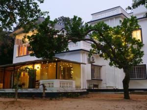 a white house with a tree in front of it at Dheer- BnB at an Artist's Abode in Shānti Niketan