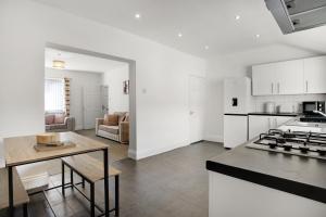 a kitchen and living room with a table and a stove at Stylish 2BR House in Ashington by Stay With Us in Ashington
