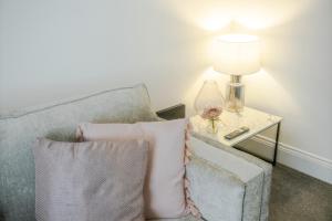 a couch with two pillows and a table with a lamp at Stylish 2BR House in Ashington by Stay With Us in Ashington +26 photos