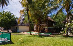 a house with a thatched roof and palm trees at Gabsgate Resort Kilifi in Kilifi +40 photos