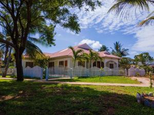 a house with a fence and palm trees at Gabsgate Resort Kilifi in Kilifi