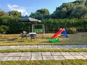 a playground with a slide and a table and an umbrella at Helen's Seaside Apartment in Nafpaktos