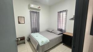 a small bedroom with a bed and a air conditioner at Homestay Atok Mus'lim Only in Jenjarum