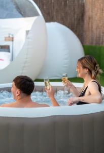 a man and woman drinking champagne in a hot tub at Burbuja El Sueño del Duque in Villanueva de Tapia