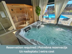 a bath tub in a room with a pool at 16 Lakes Hotel in Grabovac