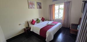 a bedroom with a bed with red pillows and a window at Hotel KSR Grand in Srikalahasti
