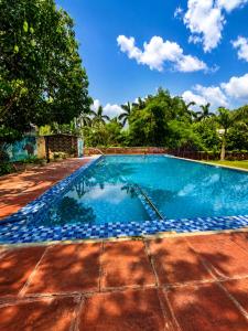 a swimming pool with blue tiles in a yard at Wildline Gold Resort in Dhikuli