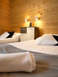 two beds in a room with wooden walls at Sarzynówka pod Sosną in Krasnobród
