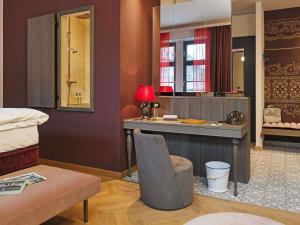 a bedroom with a desk with a bed and a chair at 25hours Hotel The Royal Bavarian in Munich +75 photos