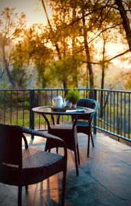 a table and chairs with a tea kettle on a balcony at The Chitai Life in Almora