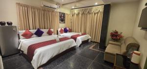 a hotel room with two beds with red and blue pillows at Hotel KSR Grand in Srikalahasti