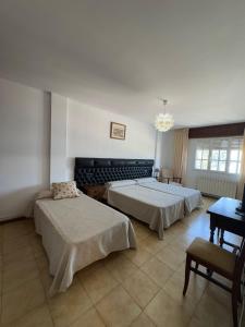 a bedroom with two beds and a chandelier at Hostal Terraza Miramar SL in Boiro