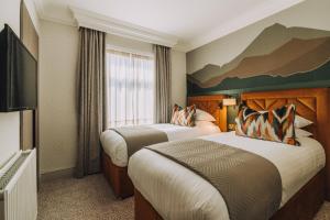 a hotel room with two beds and a tv at Skiddaw Hotel in Keswick