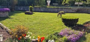 a garden with flowers in a yard with a fence at La Halte D'Aristide - Parking in Cravanche +11 photos