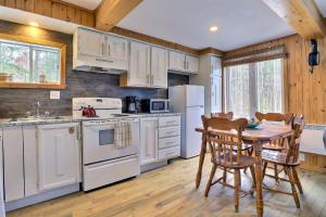 a kitchen with white appliances and a table with chairs at Spa & Sauna - Chalet de l'Ours noir in Notre-Dame-Des-Bois
