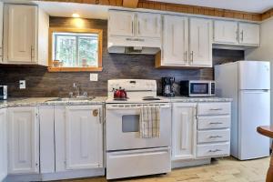 a kitchen with white cabinets and a white refrigerator at Spa & Sauna - Chalet de l'Ours noir in Notre-Dame-Des-Bois +13 photos