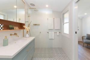 a white bathroom with a sink and a mirror at Lava House WIFI central heating cooling CBD in Warrnambool +20 photos