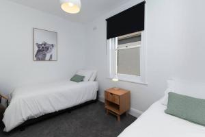 a bedroom with two beds and a window at Lava House WIFI central heating cooling CBD in Warrnambool