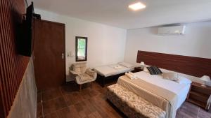 a bedroom with a bed and a chair and a table at Pousada Castelinho in São Sebastião