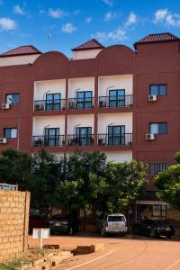 a red building with cars parked in front of it at Akenon Appart Hotel in Ouagadougou