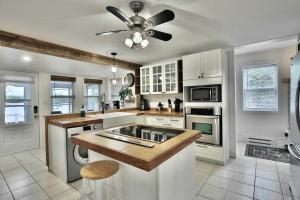 a kitchen with white cabinets and a ceiling fan at River & Nature - Nook Richelieu in Henryville +15 photos