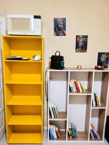 a kitchen with yellow and white shelves and a microwave at Mala & Café in Curitiba