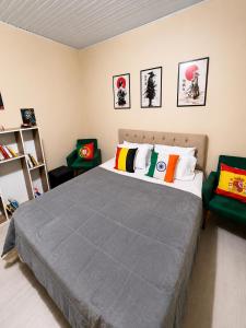 a bedroom with a bed and two green chairs at Mala & Café in Curitiba