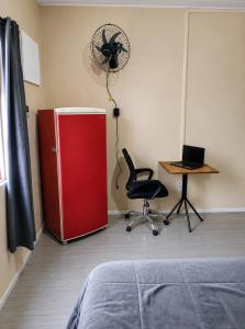 a room with a red refrigerator and a chair and a desk at Mala & Café in Curitiba