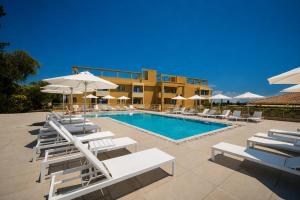 a pool with chairs and umbrellas next to a building at Tessera Boutique Hotel & Villas Collection in Gouvia