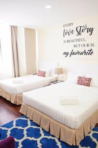 two beds in a room with a sign on the wall at TY Hotel in Kuala Terengganu
