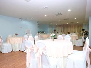 a room with white tables and chairs with white bows at TY Hotel in Kuala Terengganu +35 photos