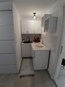 a small kitchen with white cabinets and a sink at Garsoniera Serena in Saturn +4 photos