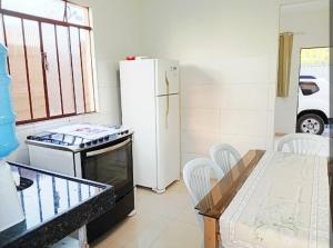 a kitchen with a refrigerator and a table with chairs at Casa 2 quartos com garagem in Divinópolis