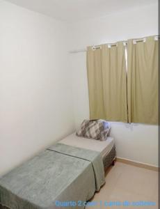 a small bedroom with a bed and a window at Casa 2 quartos com garagem in Divinópolis