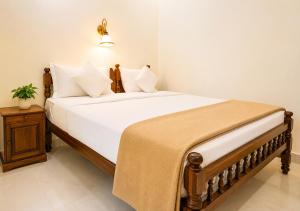 a bedroom with a bed with white sheets and pillows at Aditi in Thekkady